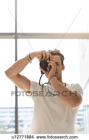 Man taking photo, glass wall in background View Large Photo Image Picture - Man taking photo, glass wall in background. Fotosearch