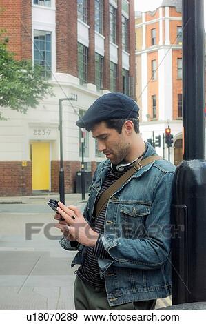 Stock Photo - Man texting by lamp post, London, UK. Fotosearch