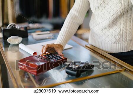 Man using calculator in clothes shop View Large Photo Image Stock Photo - Man using calculator in clothes shop. Fotosearch