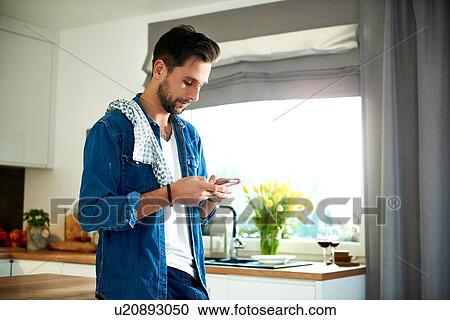 Man using smartphone in kitchen View Large Photo Image Stock Image - Man using smartphone in kitchen. Fotosearch