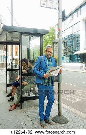 Stock Image - Man waiting at bus stop, London, UK. Fotosearch