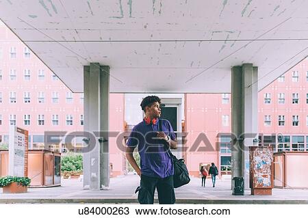 Stock Image - Man waiting under building, Milan, Italy. Fotosearch
