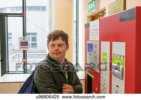 Stock Photography - Man with down syndrome at ticket machine in train station, Galway, Ireland. Fotosearch