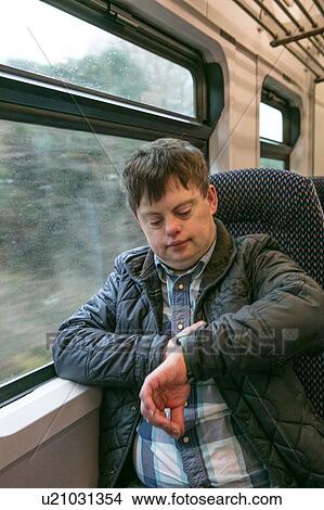 Man with down syndrome checking time on train View Large Photo Image Picture - Man with down syndrome checking time on train. Fotosearch