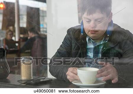 Man with down syndrome having coffee by cafe window View Large Photo Image Stock Image - Man with down syndrome having coffee by cafe window. Fotosearch