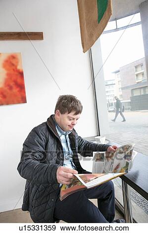 Man with down syndrome reading newspaper by cafe window View Large Photo Image Stock Photo - Man with down syndrome reading newspaper by cafe window. Fotosearch