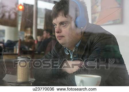 Man with down syndrome using headphones by cafe window View Large Photo Image Stock Photograph - Man with down syndrome using headphones by cafe window. Fotosearch