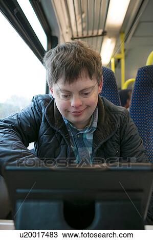 Man with down syndrome watching film on digital tablet on train View Large Photo Image Stock Image - Man with down syndrome watching film on digital tablet on train. Fotosearch