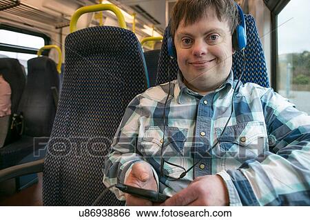 Man with down syndrome with using headphones and cell phone on train View Large Photo Image Stock Photograph - Man with down syndrome with using headphones and cell phone on train. Fotosearch