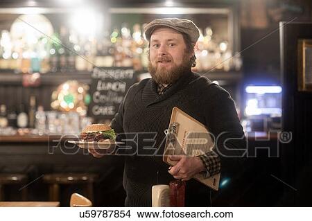 Man with plate of burger and menu in pub View Large Photo Image Picture - Man with plate of burger and menu in pub. Fotosearch