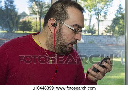 Stock Photo - Man with visual impairment listening to his phone. Fotosearch