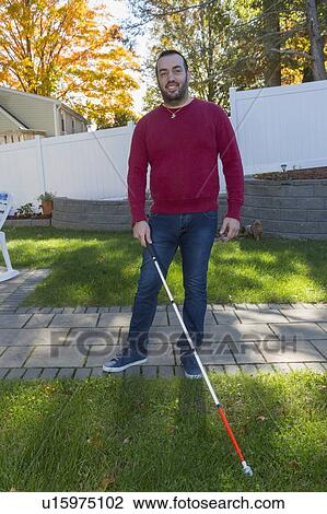 Stock Image - Man with visual impairment using his cane outdoors. Fotosearch