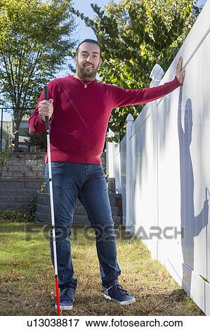 Stock Photo - Man with visual impairment using his cane outdoors. Fotosearch