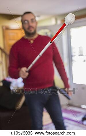 Stock Image - Man with visual impairment with his cane at home. Fotosearch