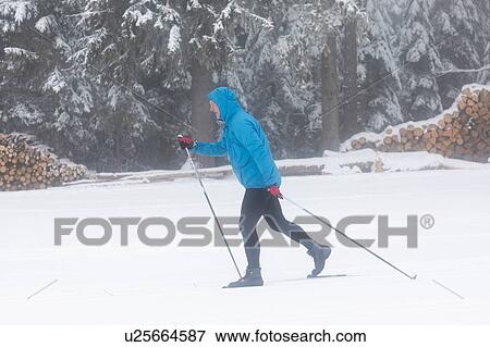 Stock Photo - Mature man cross country skiing in forest, full length. Fotosearch