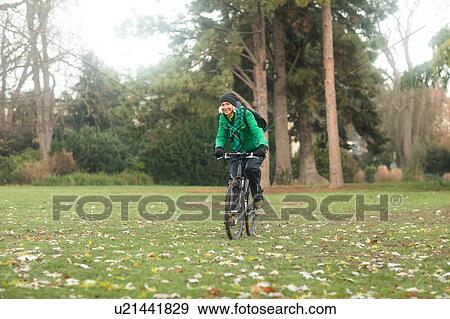 Stock Photo - Mature woman cycling in park. Fotosearch