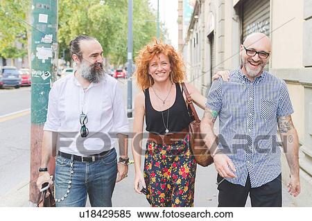 Mid adult woman and male friends laughing while strolling along on city street View Large Photo Image Stock Photography - Mid adult woman and male friends laughing while strolling along on city street. Fotosearch