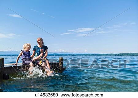 Mother and daughter cooling feet in water, Lake Starnberg, Bavaria, Germany View Large Photo Image Stock Image - Mother and daughter cooling feet in water, Lake Starnberg, Bavaria, Germany. Fotosearch
