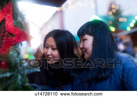 Stock Image - Mother and daughter window shopping at Christmas market, Freiburg, Baden-Wurttemberg, Germany. Fotosearch