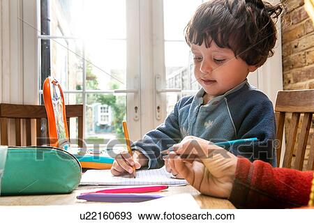 Stock Image - Mother and son writing in notebook. Fotosearch