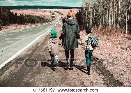 Stock Photo - Mother and sons walking along stretch of remote road, Ural, Sverdlovsk, Russia. Fotosearch