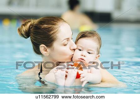 Stock Photo - Mother kissing baby in swimming pool. Fotosearch