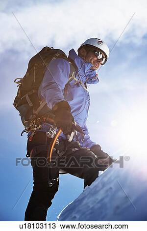 Stock Image - Mountain climber ascending mountain in bright sunlight, Chamonix, Rhone-Alps, France. Fotosearch