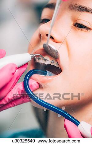 Stock Photo - Orthodontist working with little girl, cleaning dental braces.. Fotosearch