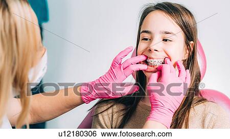 Orthodontist working with little girl, fixing dental braces. View Large Photo Image Stock Photograph - Orthodontist working with little girl, fixing dental braces.. Fotosearch