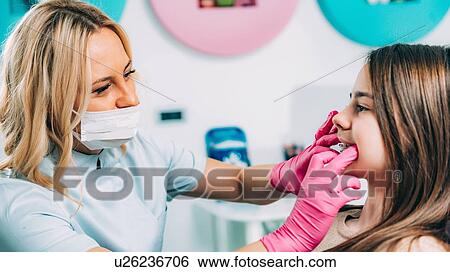 Orthodontist working with little girl, fixing dental braces. View Large Photo Image Stock Photograph - Orthodontist working with little girl, fixing dental braces.. Fotosearch