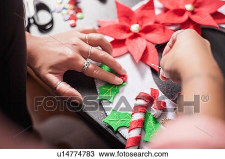 Over shoulder view of woman stitching holly berry onto christmas decoration, detail of hands View Large Photo Image Stock Image - Over shoulder view of woman stitching holly berry onto christmas decoration, detail of hands. Fotosearch