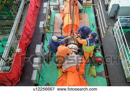 Overhead view of engineers craning large gear into place in turbine hall of nuclear power station View Large Photo Image Stock Photo - Overhead view of engineers craning large gear into place in turbine hall of nuclear power station. Fotosearch