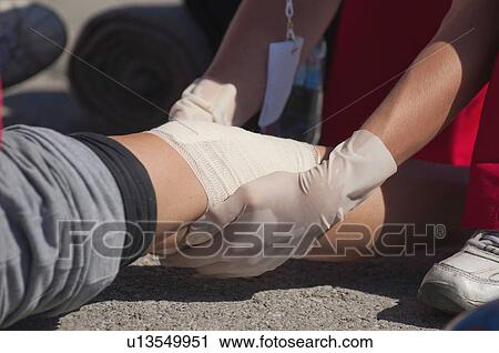 Stock Image - Paramedic treating a knee injury. Fotosearch
