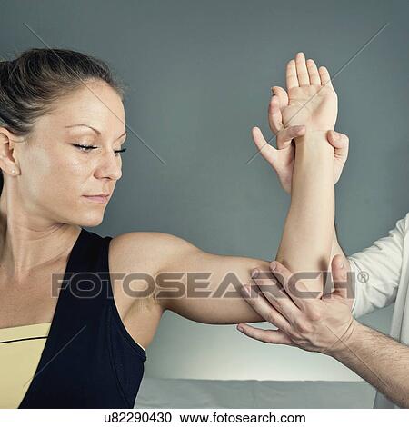 Stock Image - Physical therapist examining patient's arm. Fotosearch