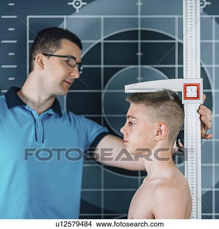 Picture - Physical therapist measuring height of teenage boy. Fotosearch