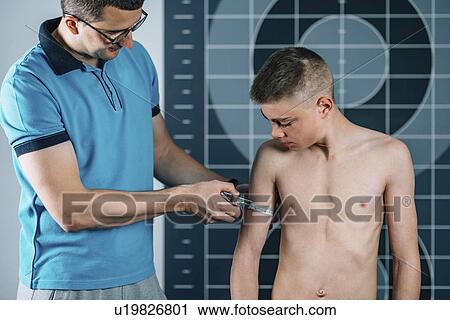 Physical therapist measuring teenage boy's arm View Large Photo Image Stock Image - Physical therapist measuring teenage boy's arm. Fotosearch