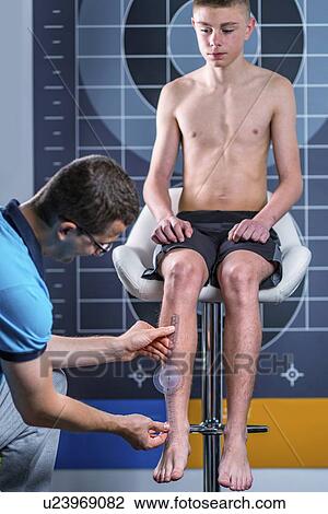 Stock Image - Physical therapist measuring teenage boy's shin. Fotosearch
