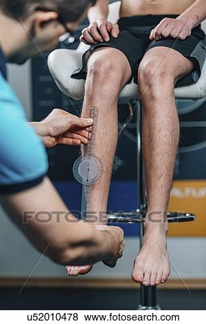 Stock Photo - Physical therapist measuring teenage boy's shin. Fotosearch