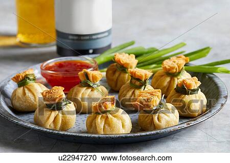 Stock Image - Plate with mini egg roll wraps with duck sauce. Fotosearch