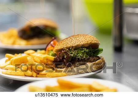Plates of hamburger and chips on commercial kitchen counter, close up View Large Photo Image Stock Photography - Plates of hamburger and chips on commercial kitchen counter, close up. Fotosearch