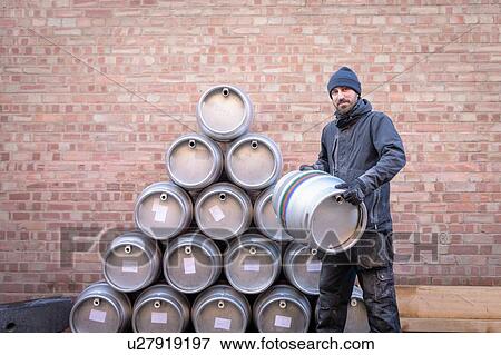 Stock Photo - Portrait of brewer by stack of barrels in small brewery. Fotosearch
