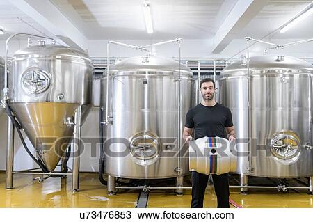 Stock Image - Portrait of brewer with barrel in small brewery. Fotosearch
