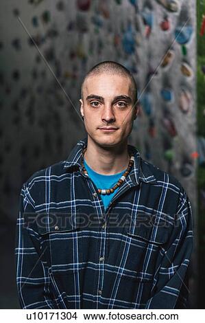 Picture - Portrait of male climber, climbing wall in background. Fotosearch