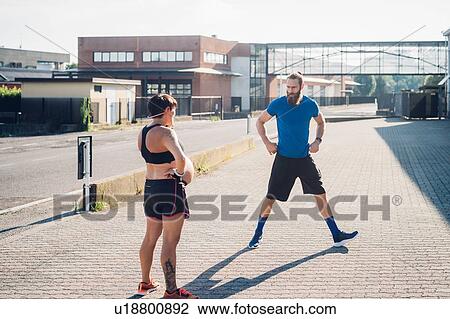 Stock Image - Pregnant woman and personal trainer working out outdoors. Fotosearch