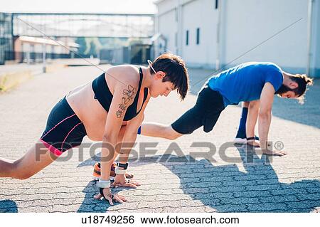 Stock Photograph - Pregnant woman and personal trainer working out outdoors. Fotosearch
