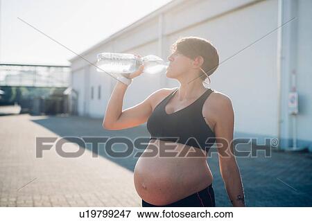 Pregnant woman having drink during workout View Large Photo Image Stock Photo - Pregnant woman having drink during workout. Fotosearch