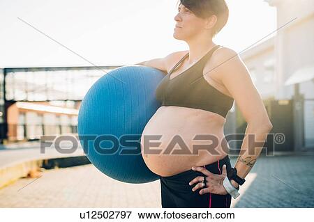 Stock Photo - Pregnant woman holding exercise ball. Fotosearch