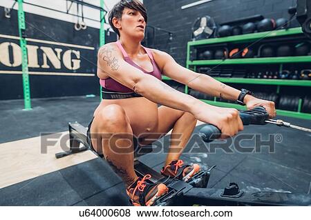 Stock Photo - Pregnant woman on rowing machine in gym. Fotosearch