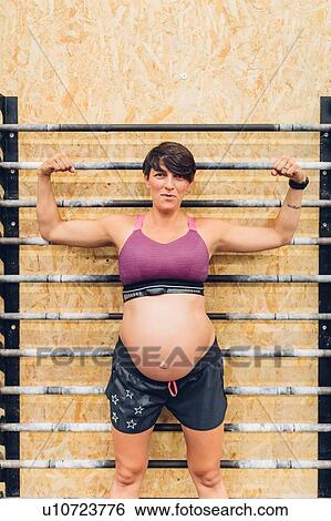 Pregnant woman standing against exercise bars View Large Photo Image Stock Photograph - Pregnant woman standing against exercise bars. Fotosearch