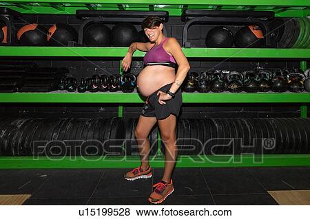 Stock Photo - Pregnant woman standing in gym. Fotosearch
